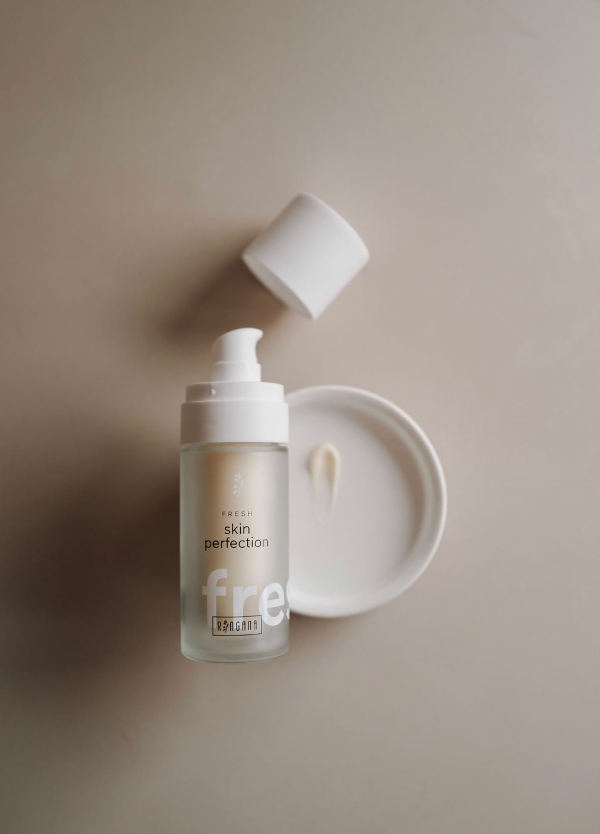 Geöffnete Pumpflasche aus Milchglas neben einer kleinen weißen Schale, von oben